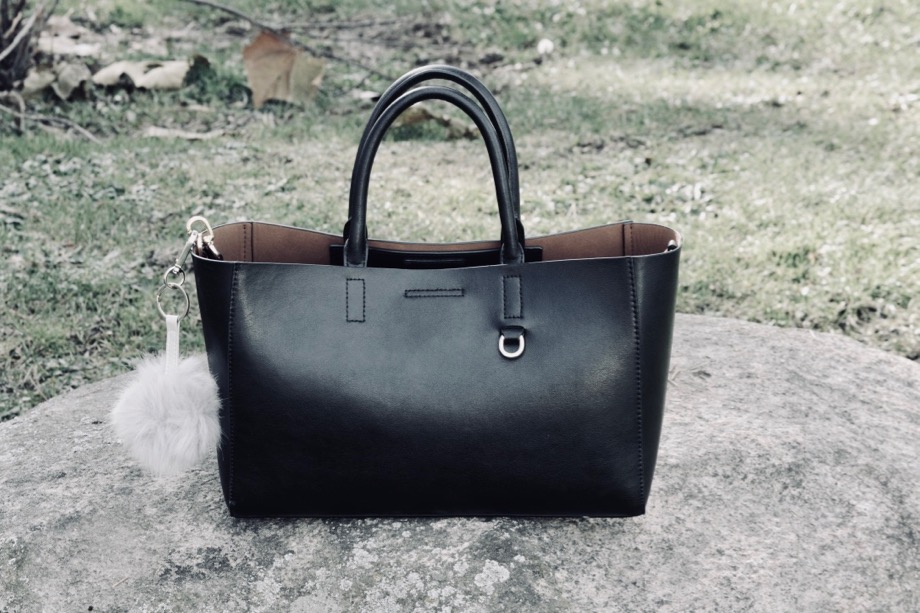 Black tote bag with a fur accessory.