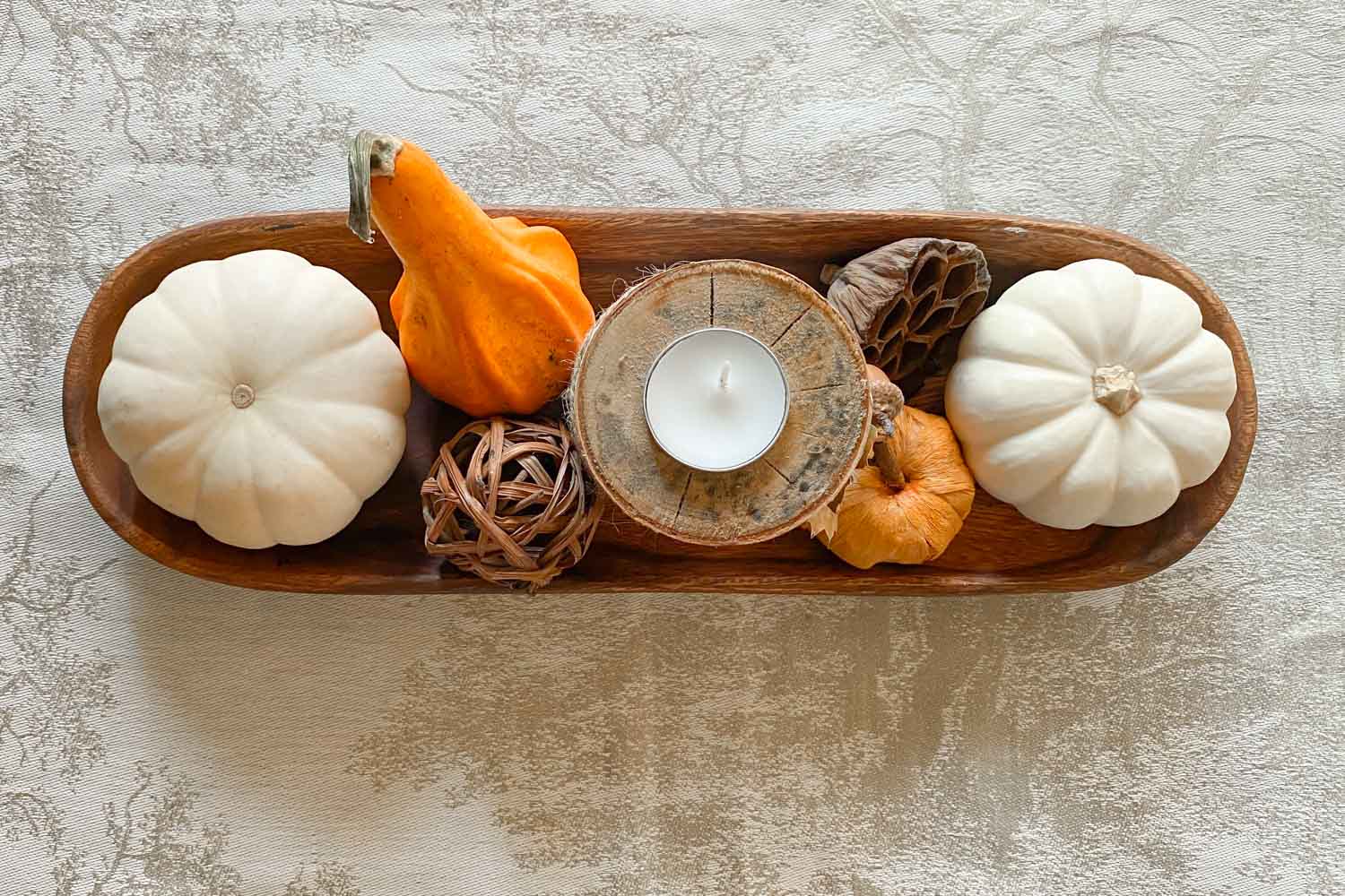 Oval wood bowl with pumpkins, gourds, a straw ball, and birch candle holder