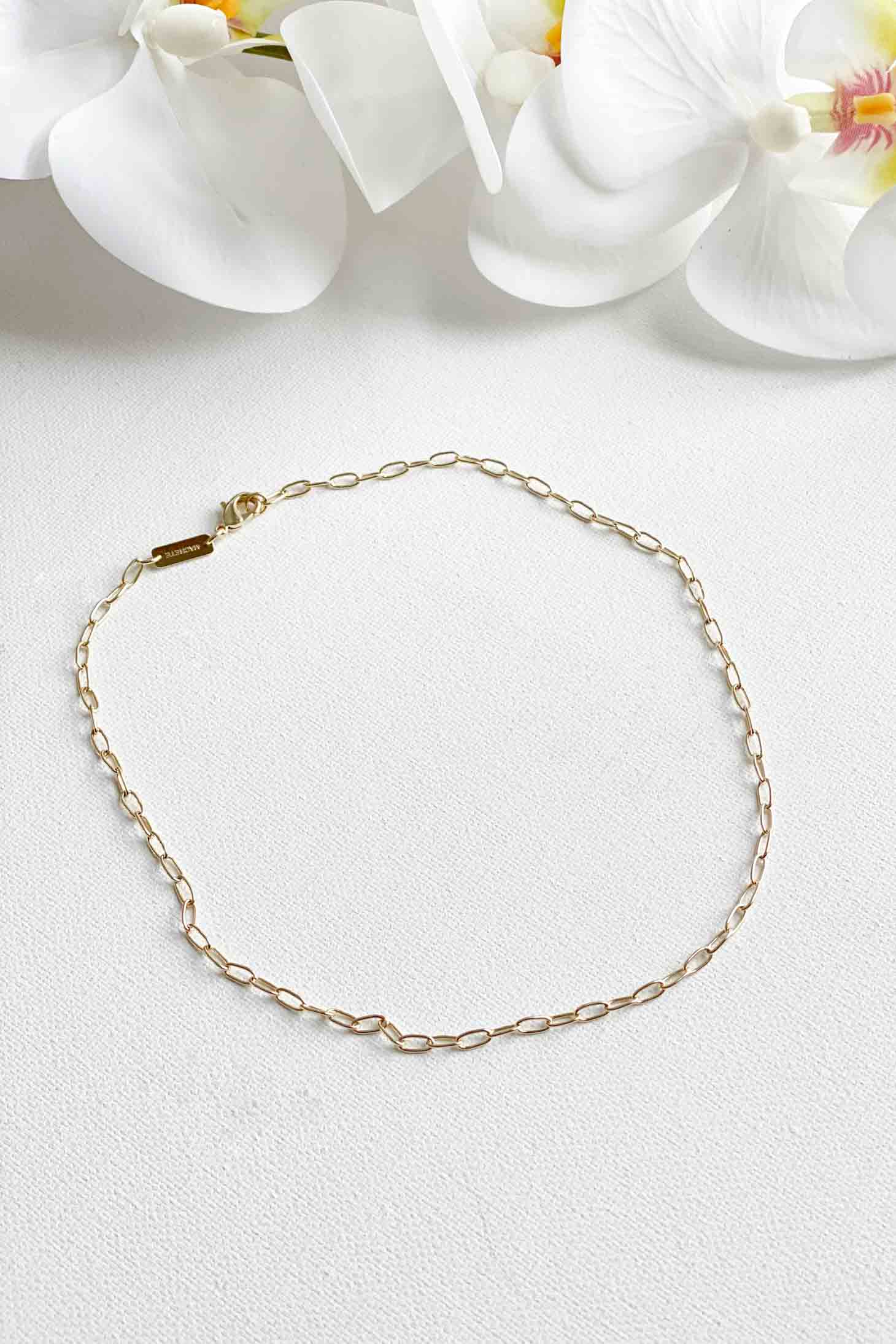 Gold paperclip chain necklace on a white background