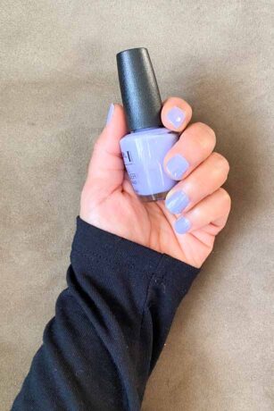 Hand showing nails painted in OPI's You're Such A Budapest (lavender) holding a bottle of the polish.