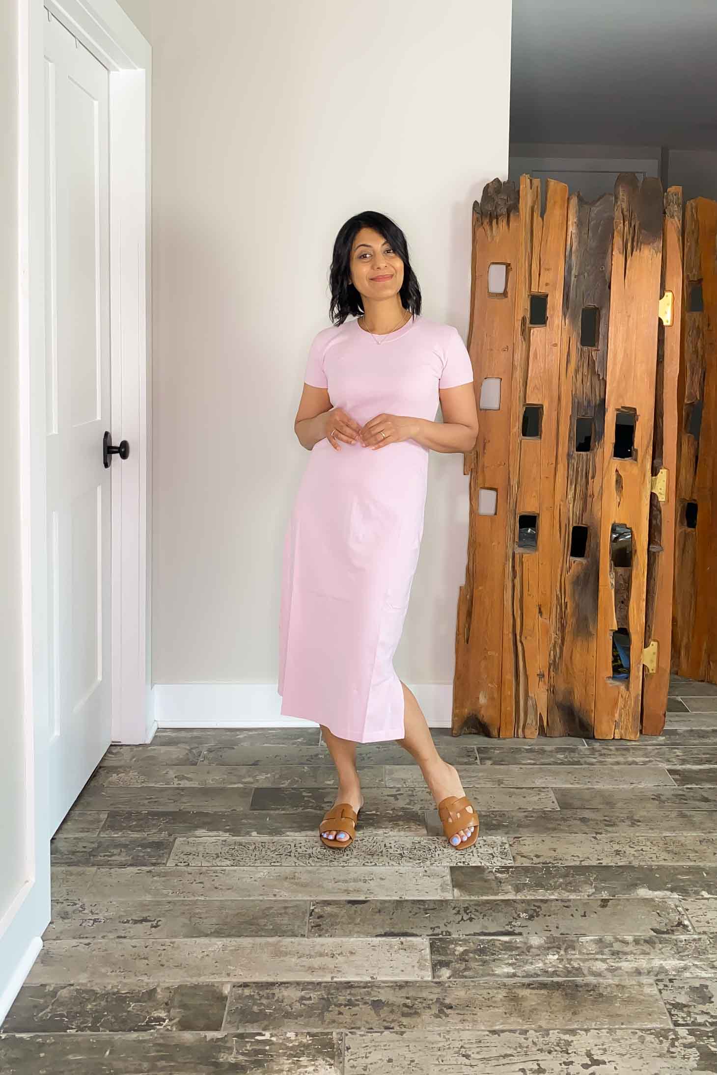 Nipa wearing a light pink t-shirt dress with tan flat sandals.