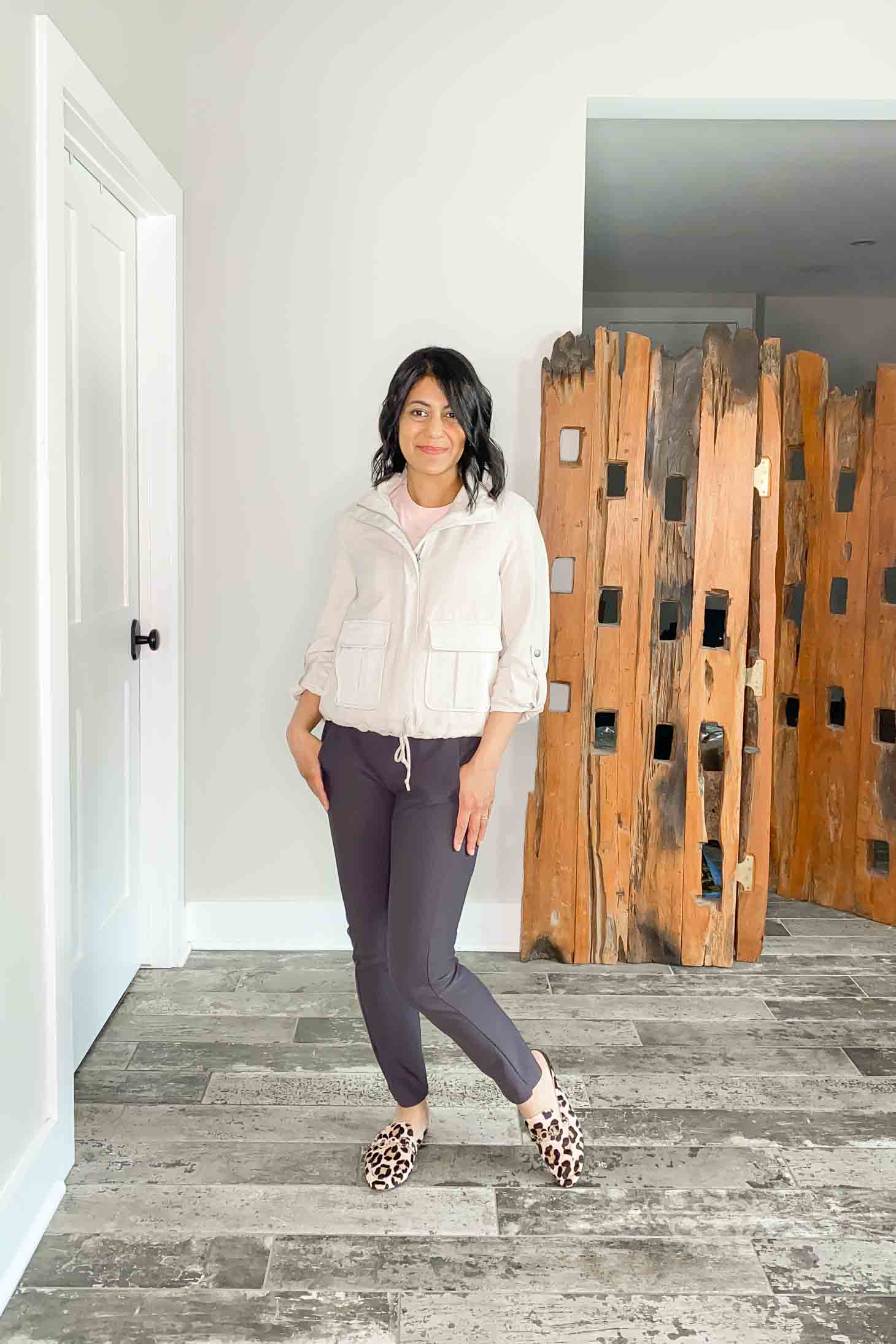 Fashionipa in a gray bomber jacket with a pink t-shirt, taupe panst and pink leopard mules.