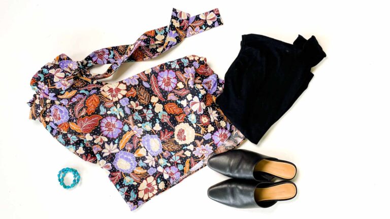 Flatlay of printed maxi skirt, black top, black mules and turquoise beaded bracelet