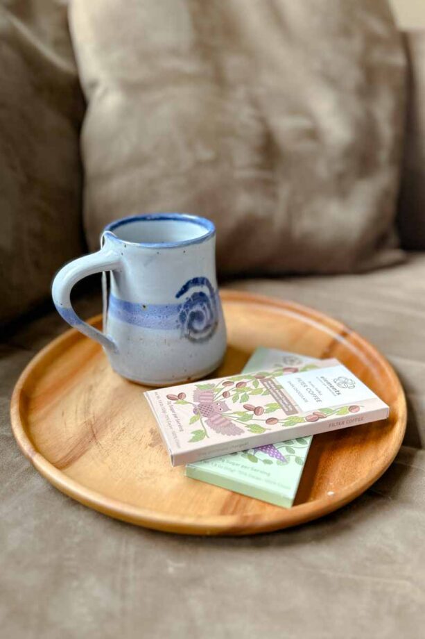 Handmade mug of tea on a round platter, with two bars on chocolate on it.