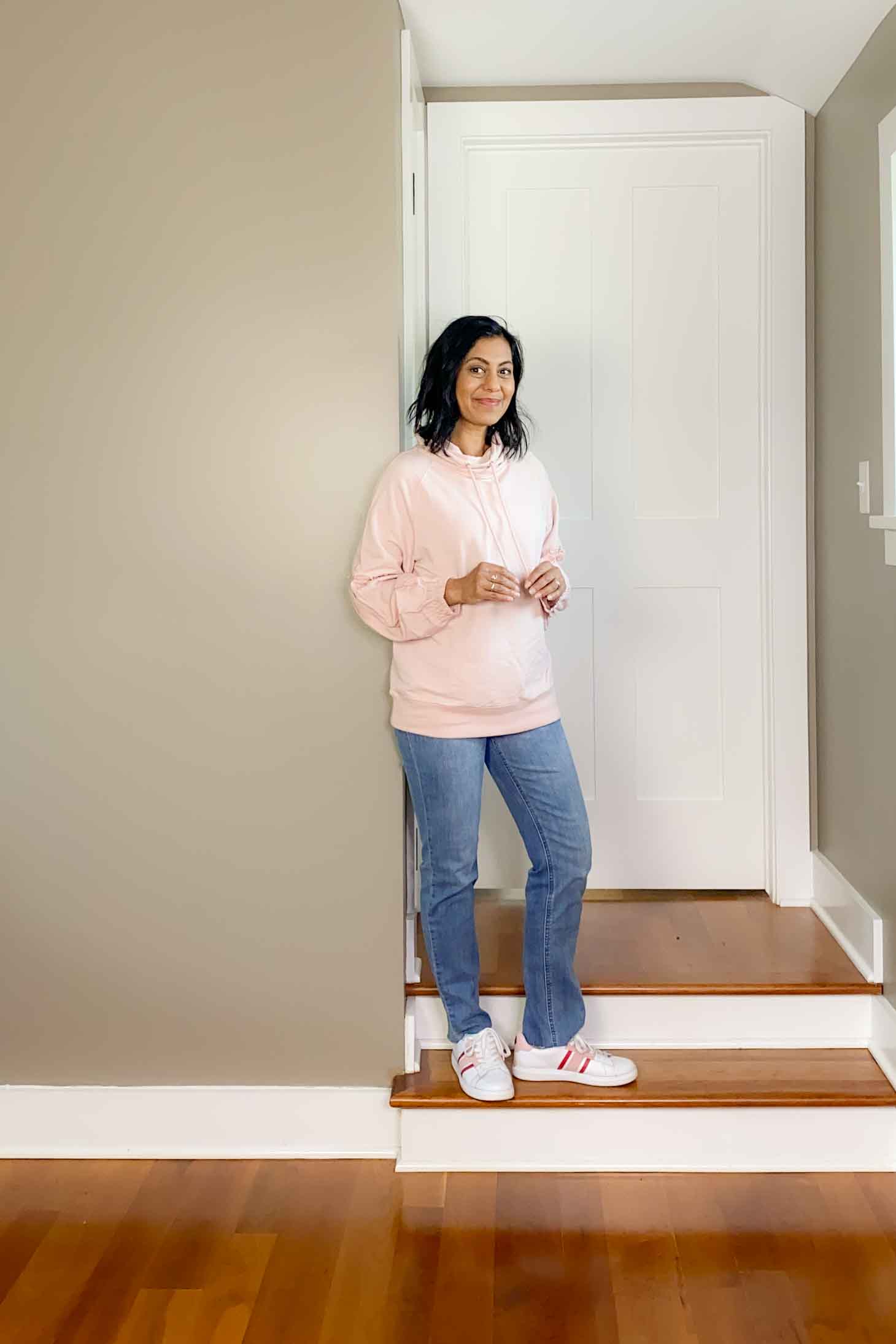 Fashionipa wearing a pink sweatshirt, jeans and white sneakers
