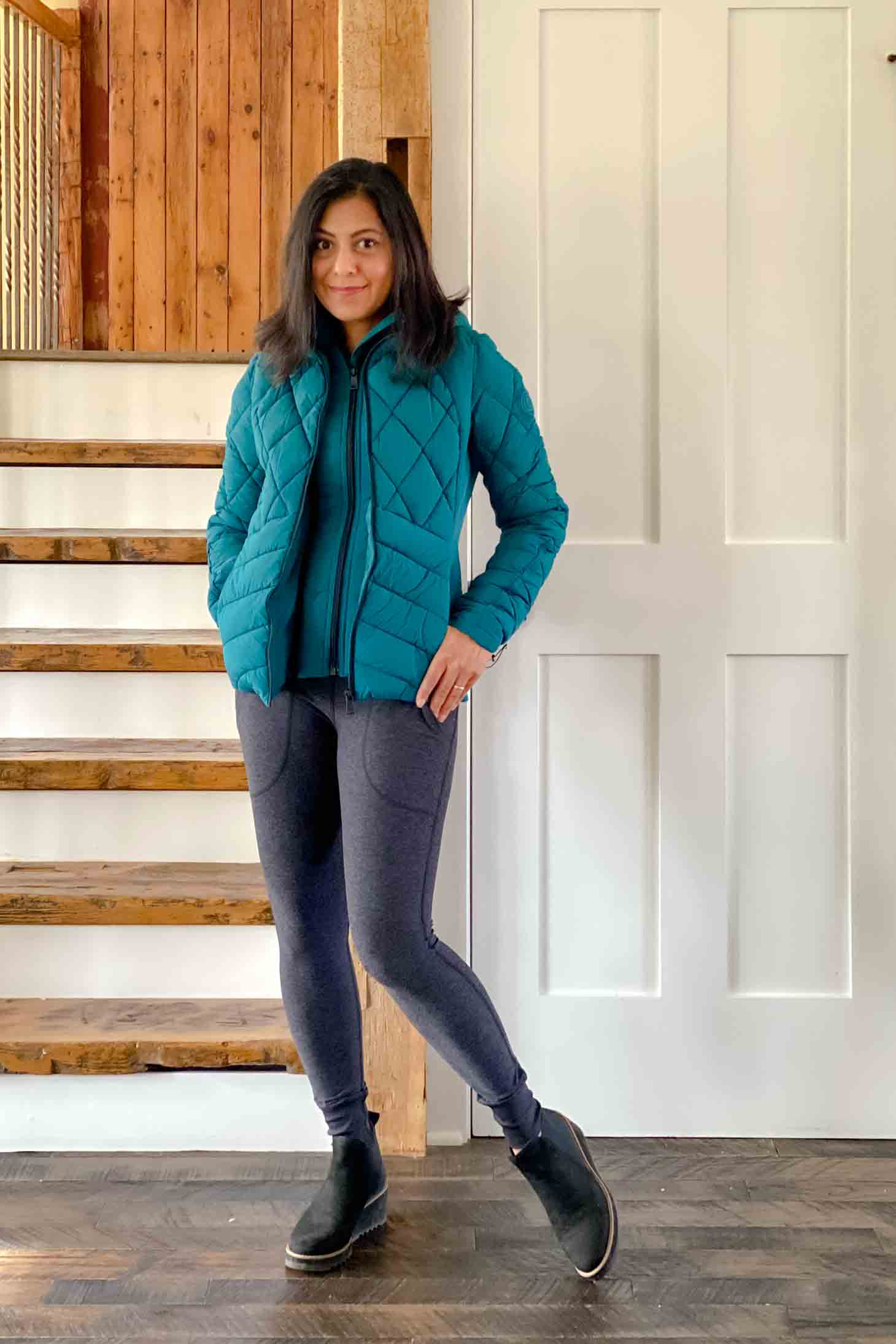 Fashionipa in a teal jacket, charcoal leggings and black boots 
