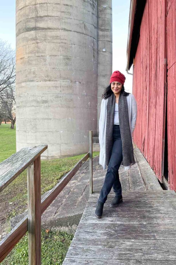 Fashionipa wearing a red beanie, gray t-shirt, cardigan and scarf and dark gray jeans.  