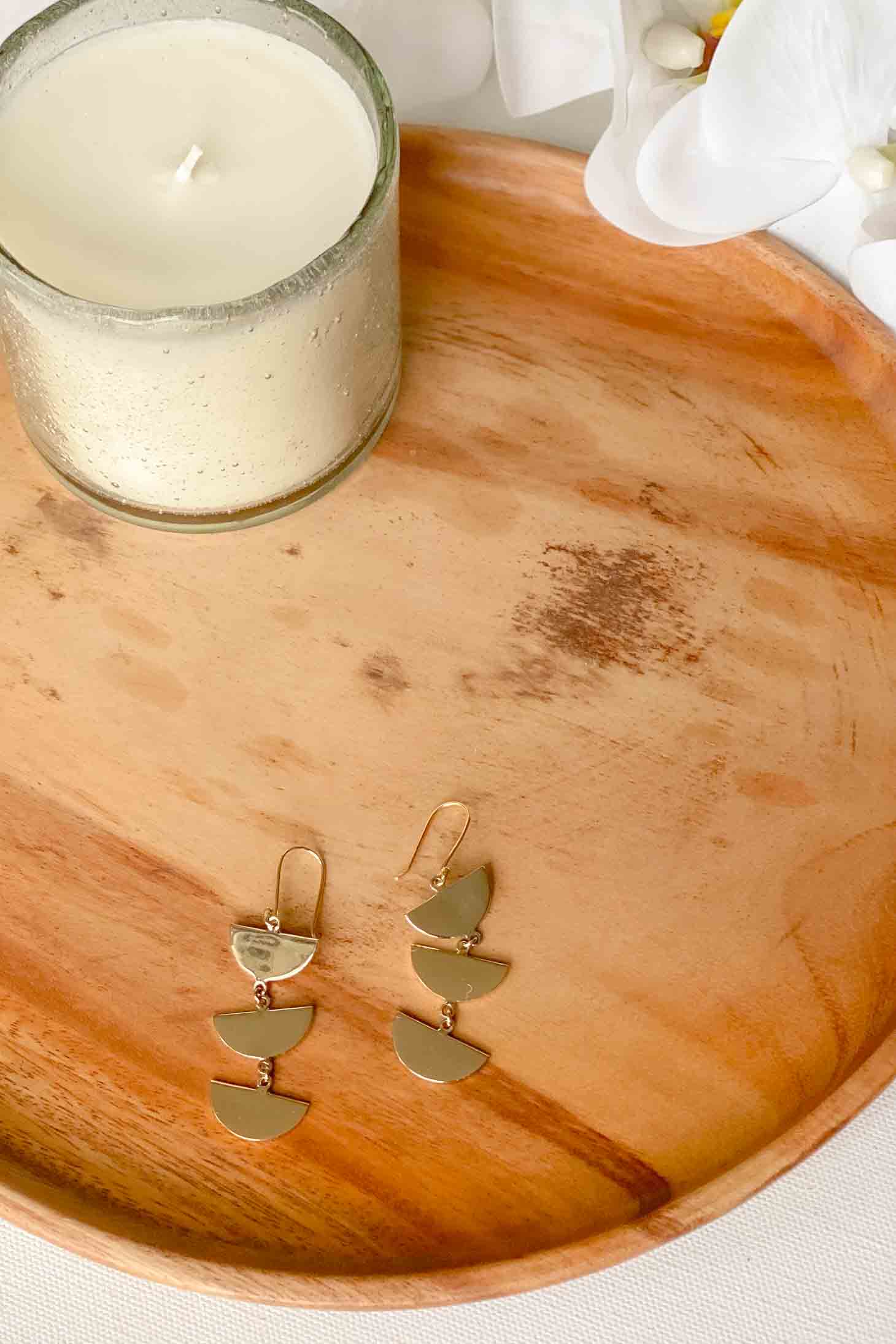Cascading gold earrings on a wooden tray