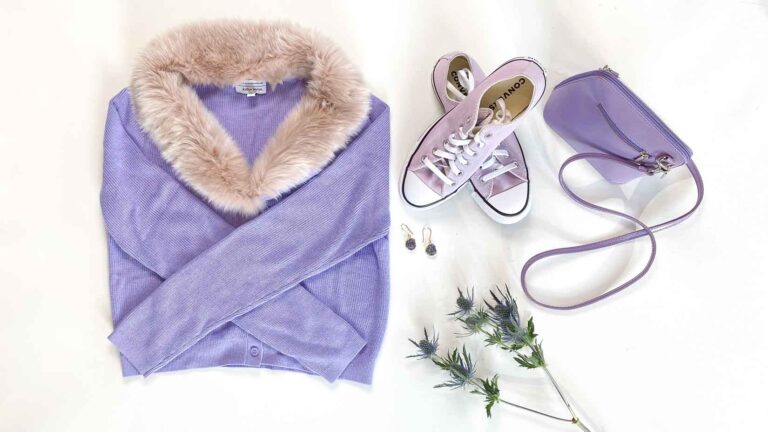 Flatlay of purple cardigan with fur trim, purple sneakers, purple handbag and amethyst earrings