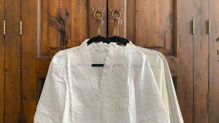 Three white blouses hanging on a wooden armoire
