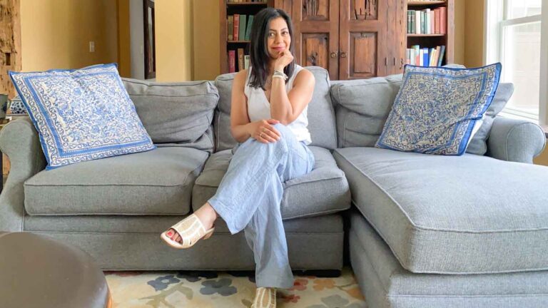 Fashionipa sitting on a gray couch wearing a white tank top and chambray linen pants...