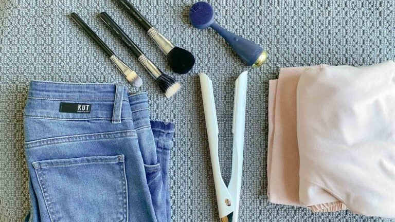 Flatlay of jeans, makeup brushes, facial cleaning device and sweatshirt