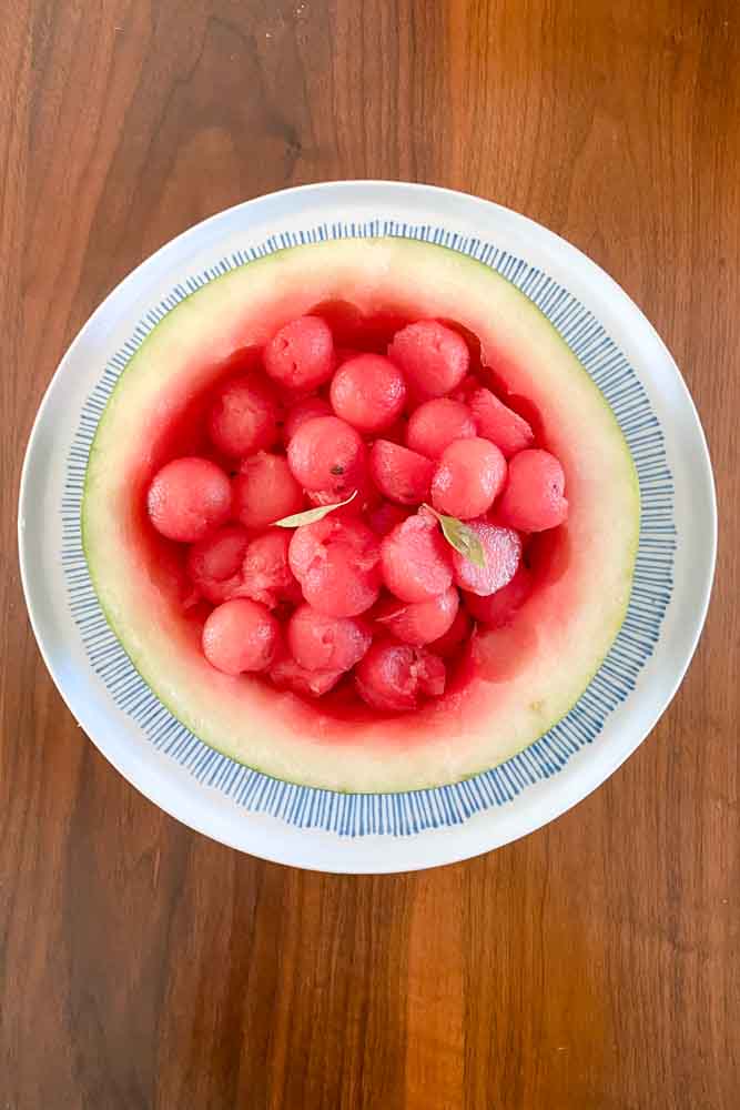 Watermelon bowl with watermelon balls and basil leaves