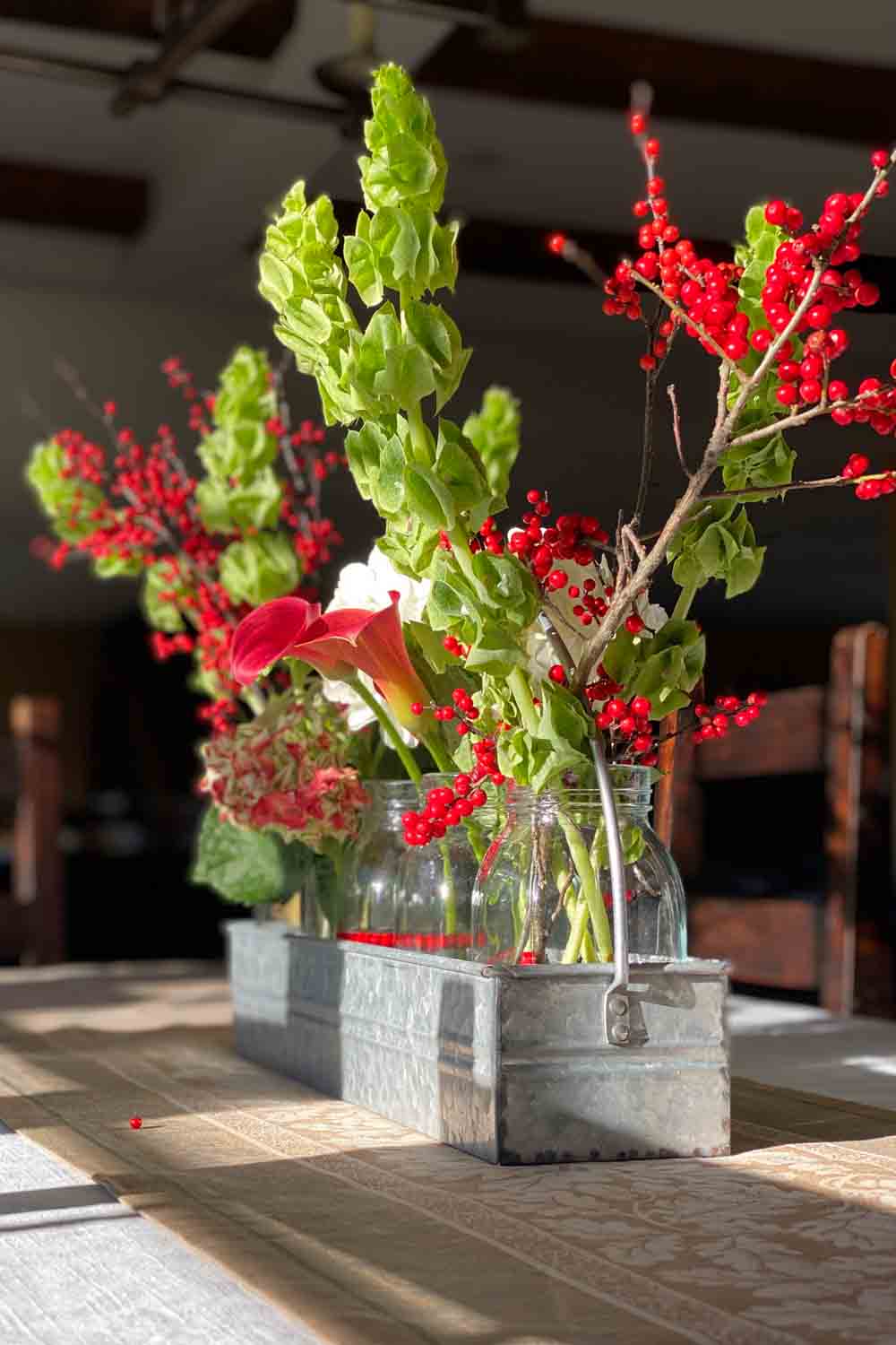 Red and green floral arrangement in galvanized container
