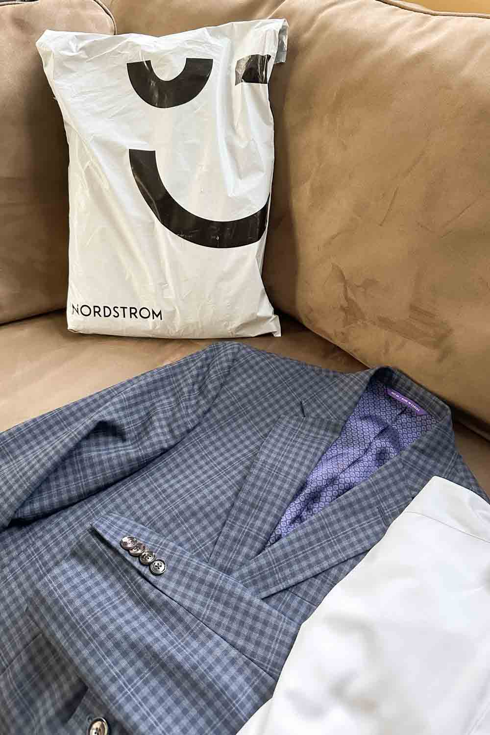 Image of a Nordstrom package, a check blazer and white shirt on a tan couch.