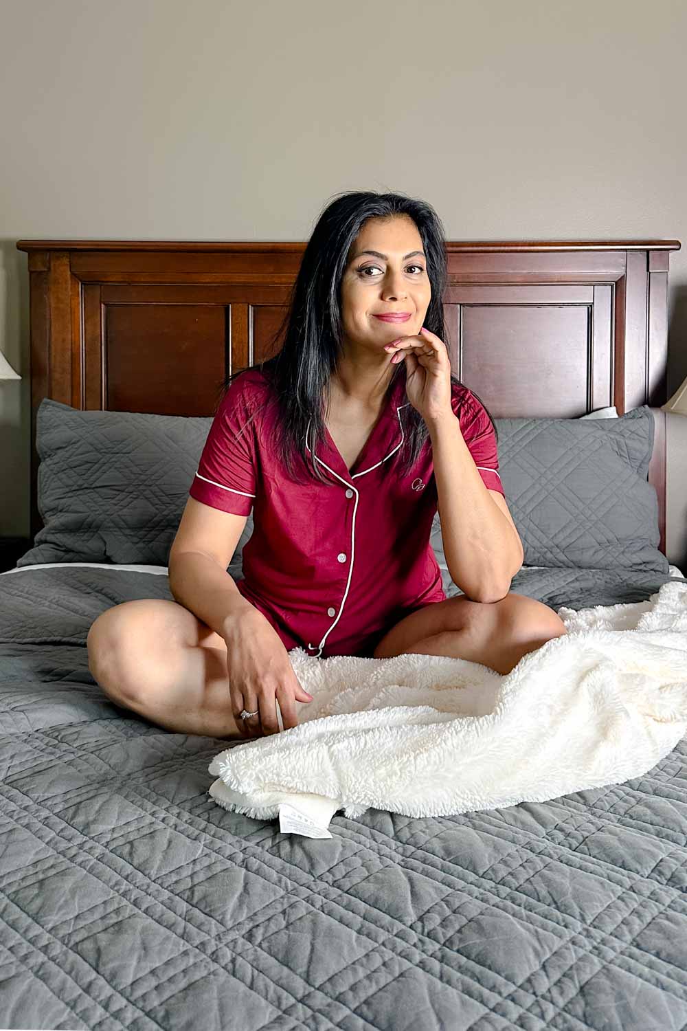 Fashionipa (Nipa) sitting on a bed wearing red short-sleeved button-front pajamas with shorts.