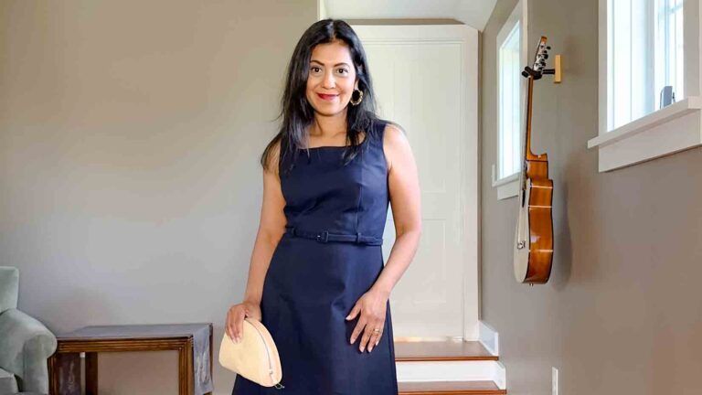 Fashionipa (Nipa) wearing a navy dress holding a straw moon-shaped clutch.