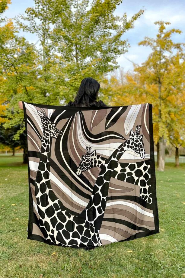Fashionipa (Nipa) holding a large square scarf with a giraffe motif.