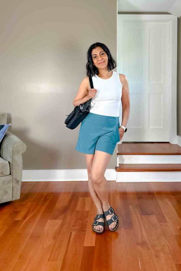 Fashionipa (Nipa) wearing a white tank, blue-green shorts and Birkenstocks. She is carrying a nylon water bottle holder.