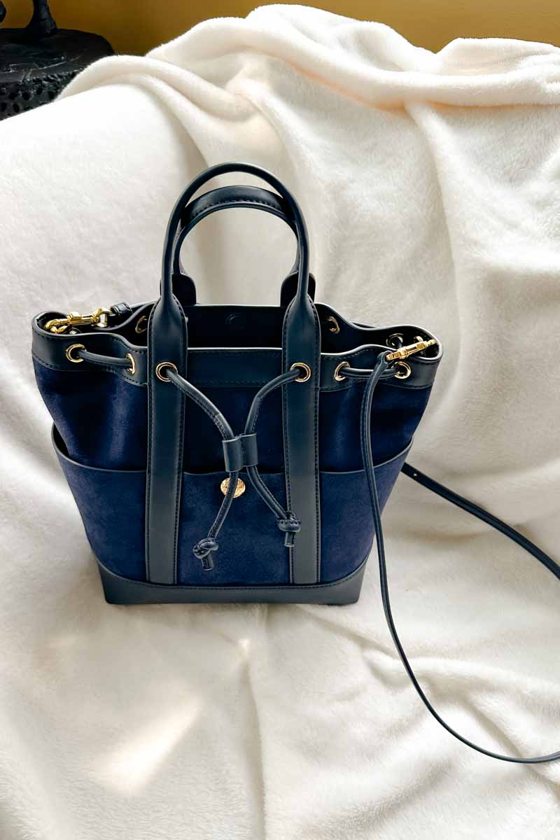 Navy suede and leather bucket bag with gold hardware and a crossbody strapo.  