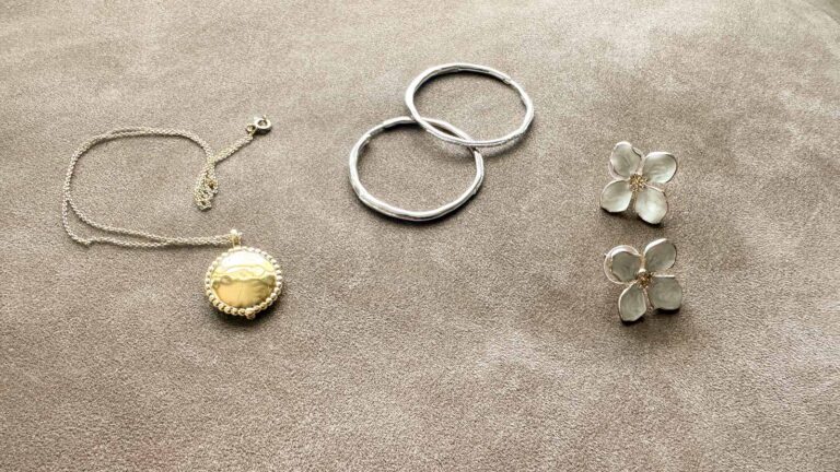 Image of a chunky gold locket, wavy hoops and flower earrings.