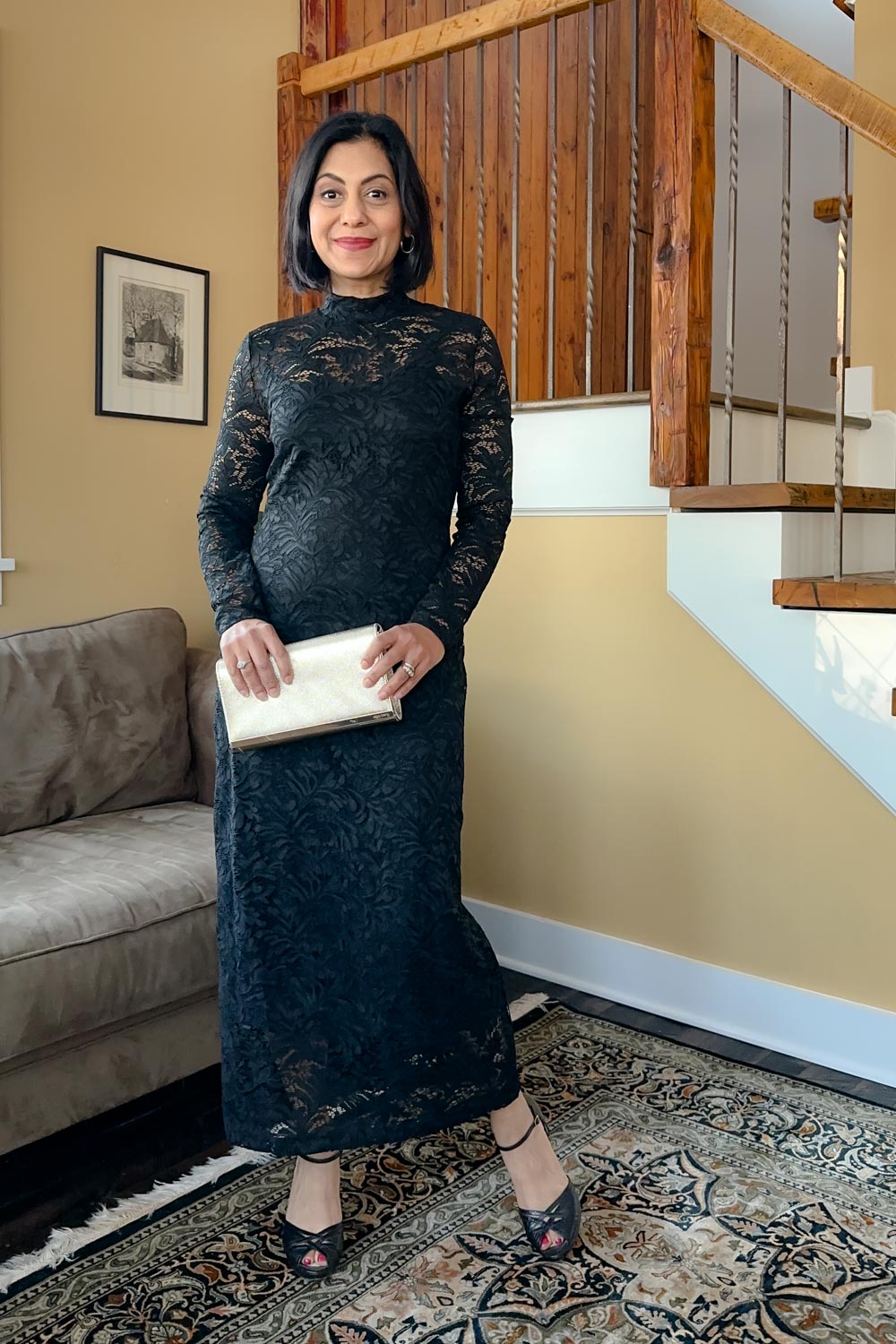 Fashionipa (Nipa) wearing a black lace dress and heels, holding a gold clutch.