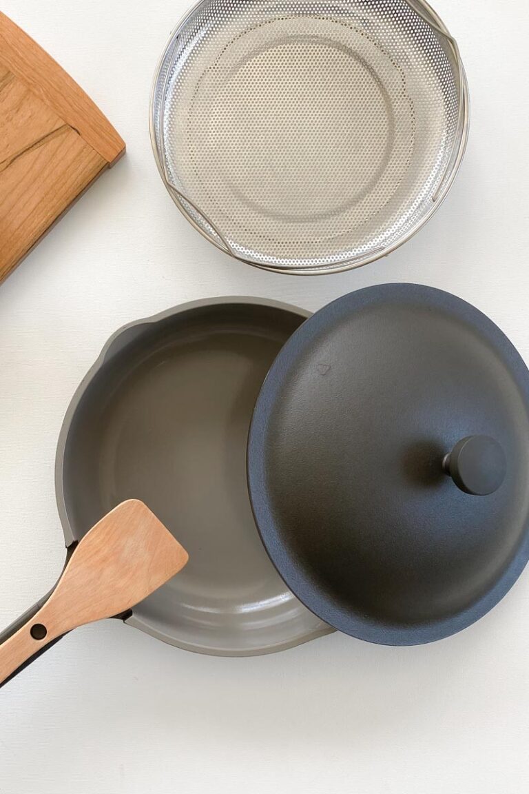 Birdseye view of the Always Pan in Char (gray) with a wooden spoon and steamer basket.