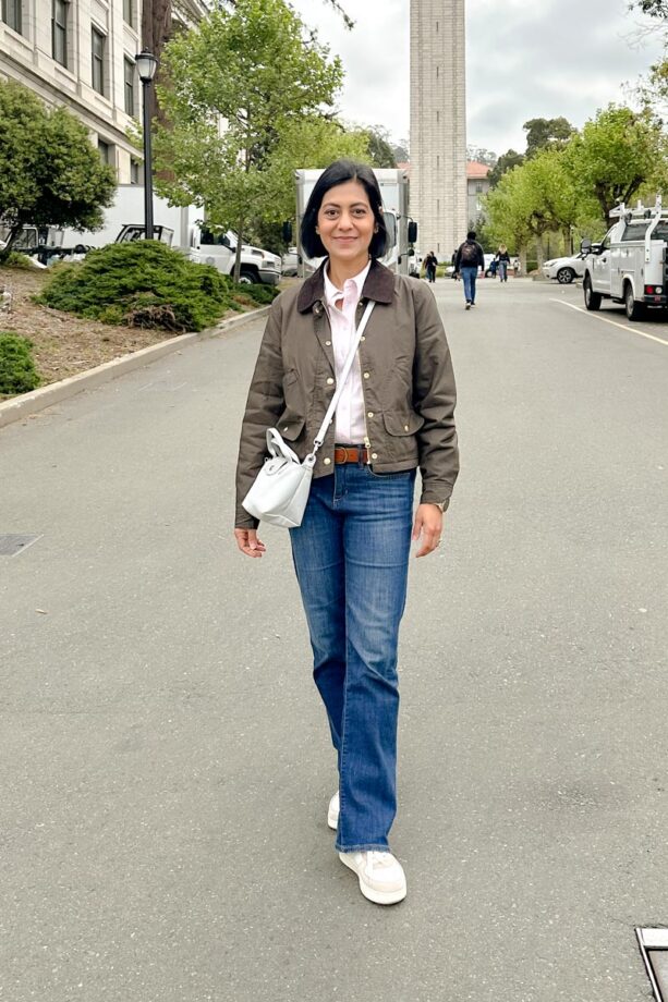 Fashionipa (Nipa) wearing pink shirt, brown jacket, jeans and sneakers with a nylon crossbody across her shoulder.
