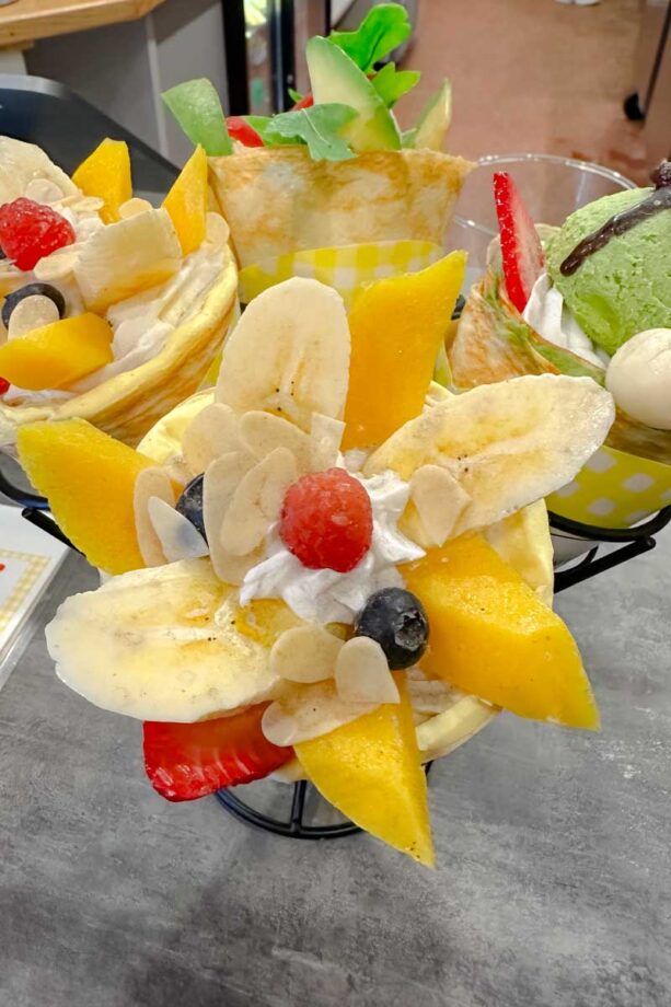 Bananas, mangoes and other fruit in a crepe cone.