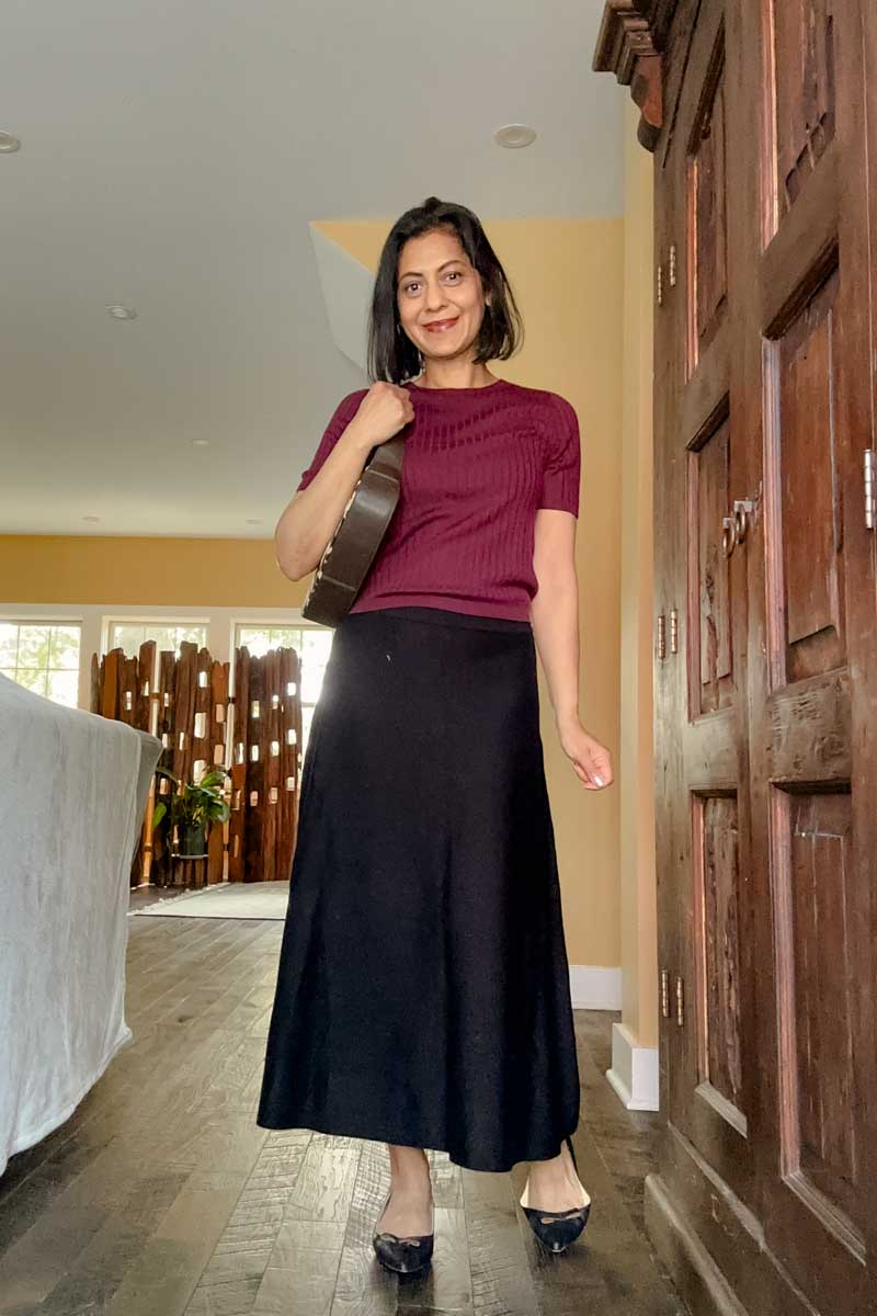 Fashionipa (NIpa) wearing a burgundy ribbed short-sleeve sweater with a black skirt and flats.