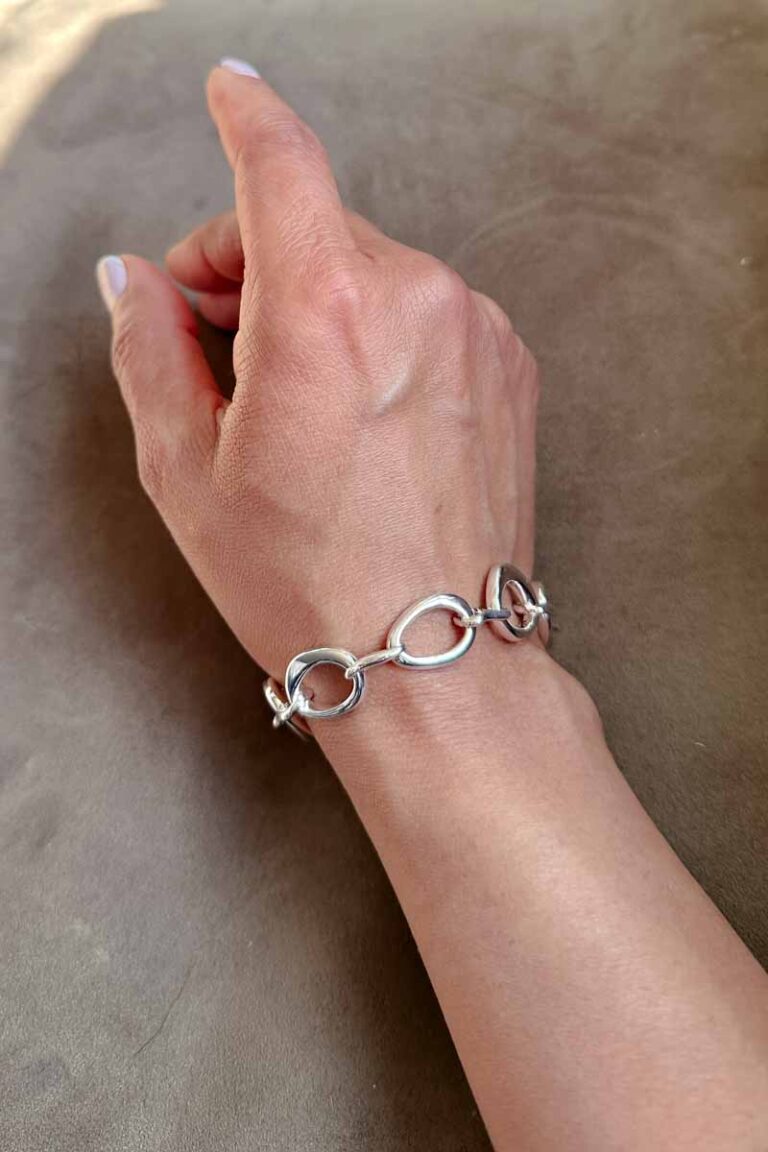 Woman's hand/wrist wearing a chain bracelet with oversized rings
