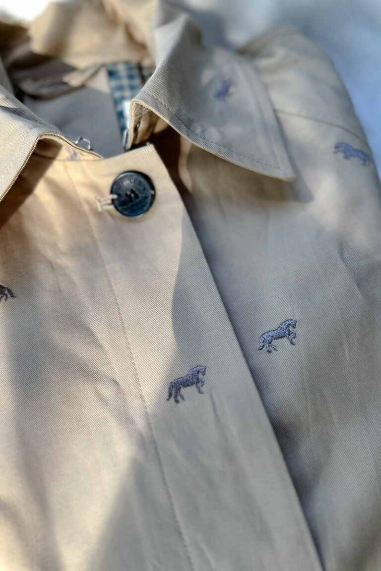 A close up of embroidered horses on tan fabric.