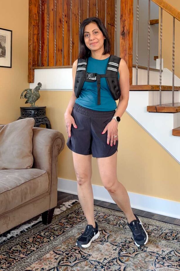 Fashionipa (Nipa) wearing a green tank top with black shorts with white piping, a weighted vest and black sneakers.