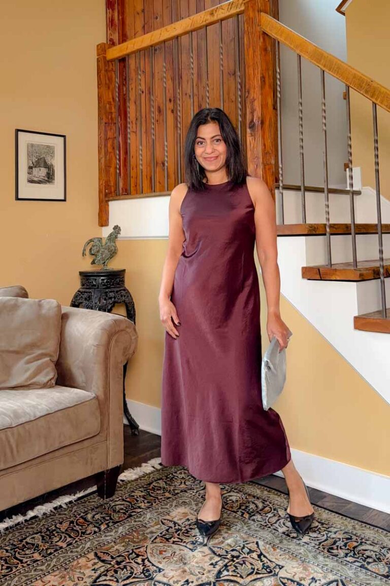 Fashionipa (Nipa) wearing a burgundy sleeveless satin midi dress with black flats - she is holding a silver clutch.