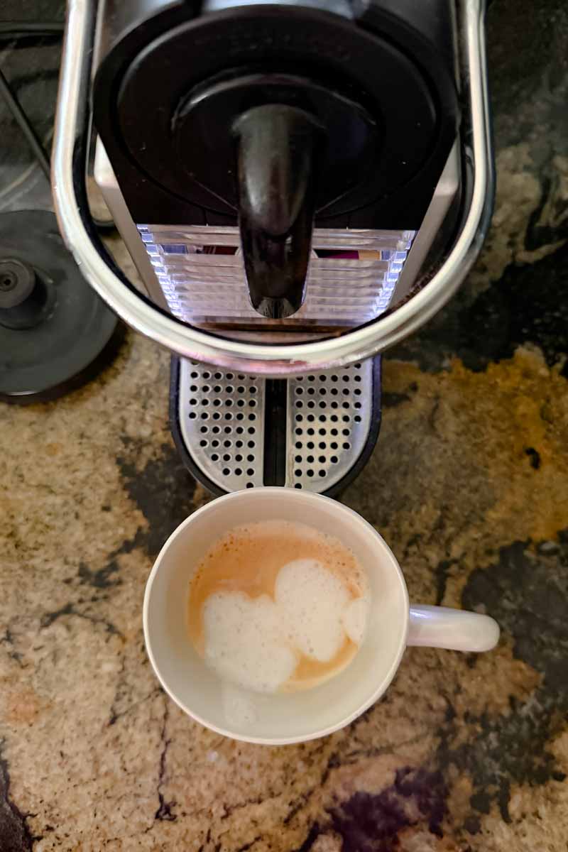 Nespresso espresso maker and a cup of frothy coffee